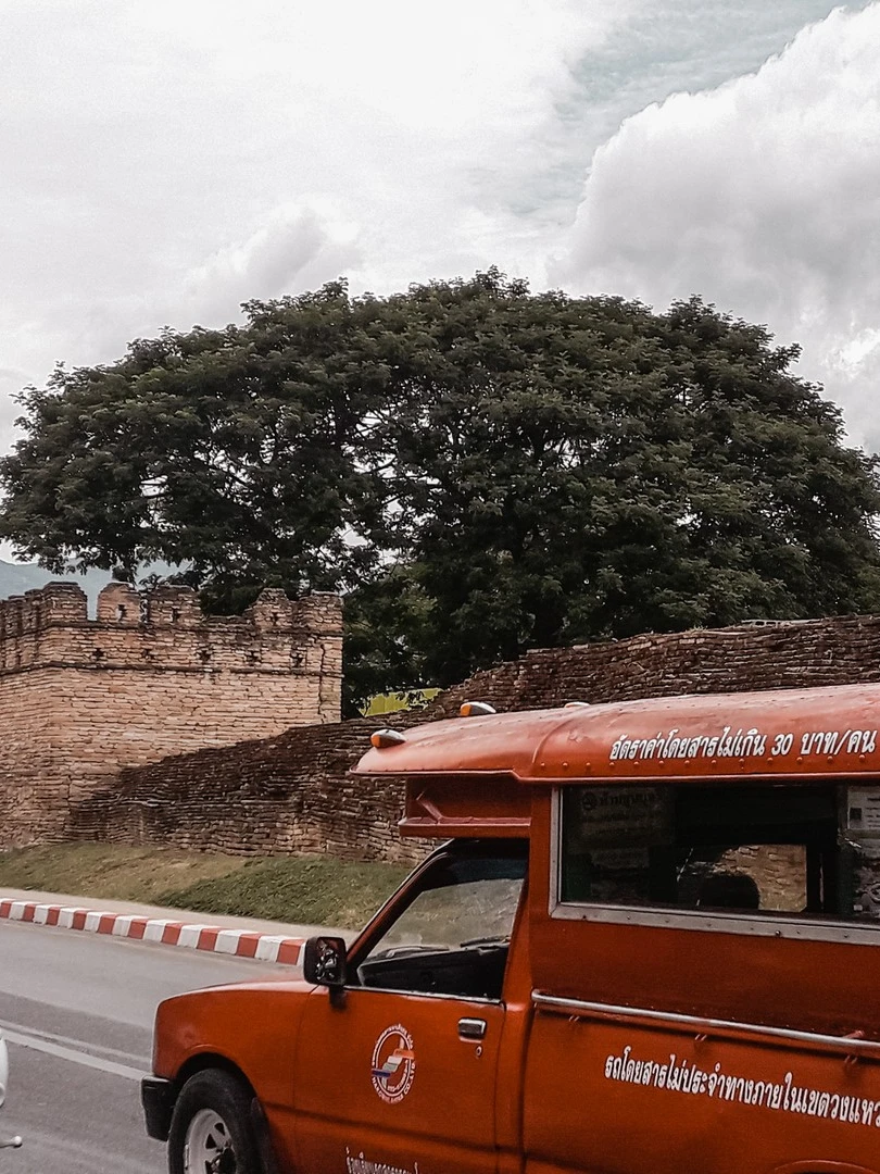 Photo 1 from Benjamin Simier’s Instagram post: Red songthaew (sort of bus that runs in almost all Thai provinces) front the Tha Pae Gate in the Chiang Mai old city in Thailand 🇹🇭