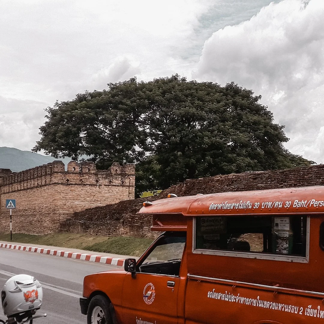 Photo 1 from Benjamin Simier’s Instagram post: Red songthaew (sort of bus that runs in almost all Thai provinces) front the Tha Pae Gate in the Chiang Mai old city in Thailand 🇹🇭