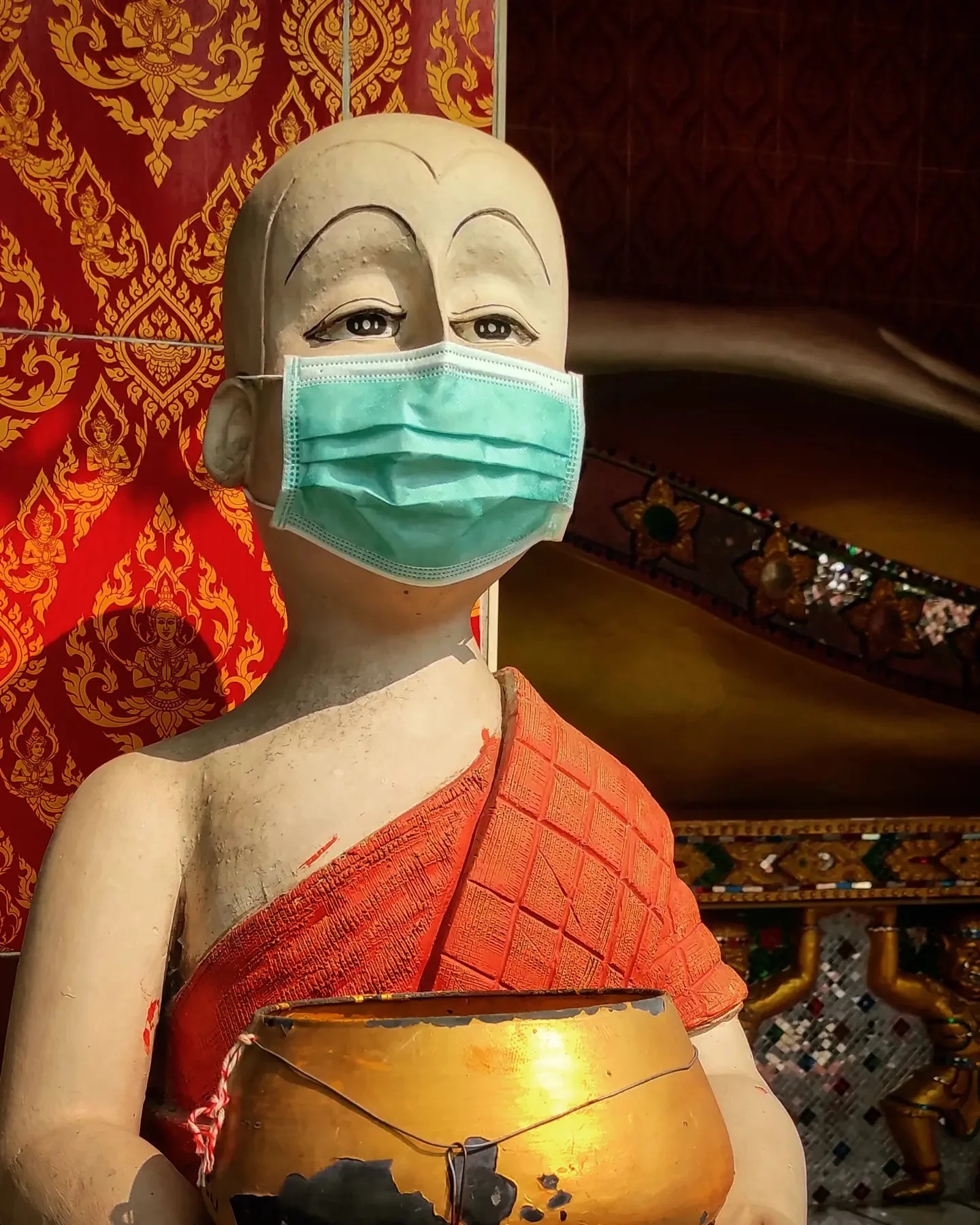 Photo 1 from Benjamin Simier’s Instagram post: in Thailand even the statues wear a mask ... let's hope the COVID stops and life gets back to normal soon. Here a monk statue with a mask 😷
