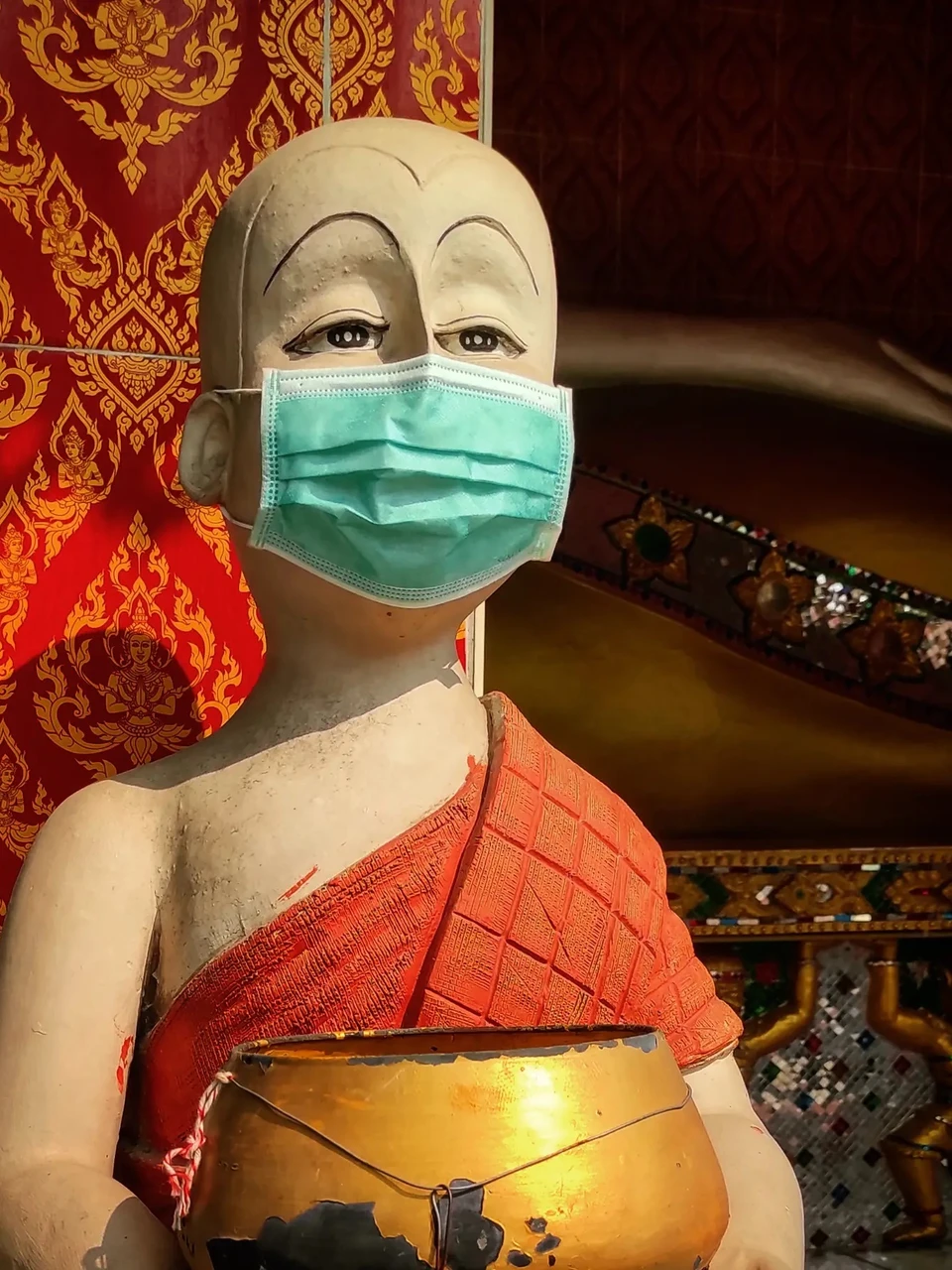 Photo 1 from Benjamin Simier’s Instagram post: in Thailand even the statues wear a mask ... let's hope the COVID stops and life gets back to normal soon. Here a monk statue with a mask 😷