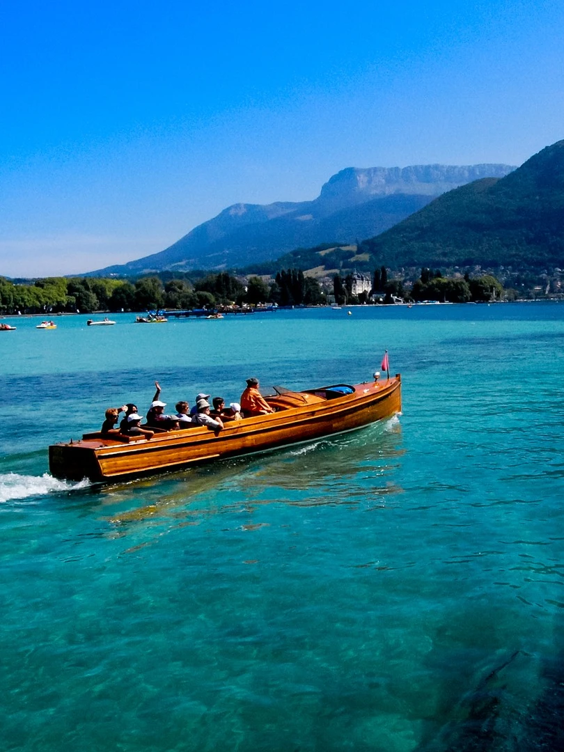 Photo 1 from Benjamin Simier’s Instagram post: Wooden boat facing the mountains on the Annecy lake in France 🇫🇷